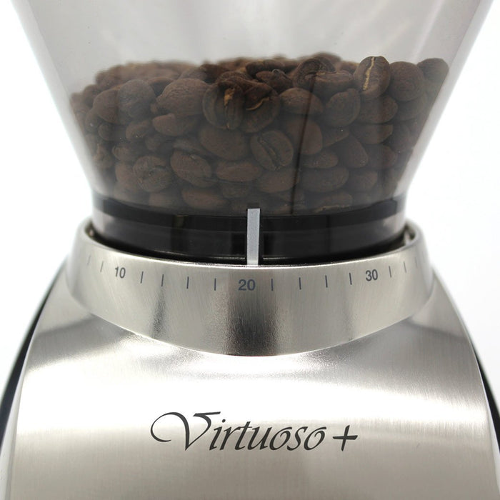 Close up of turn dial of Baratza Virtuoso+ Burr Coffee Grinder with coffee beans inside bean hopper displayed on a white background