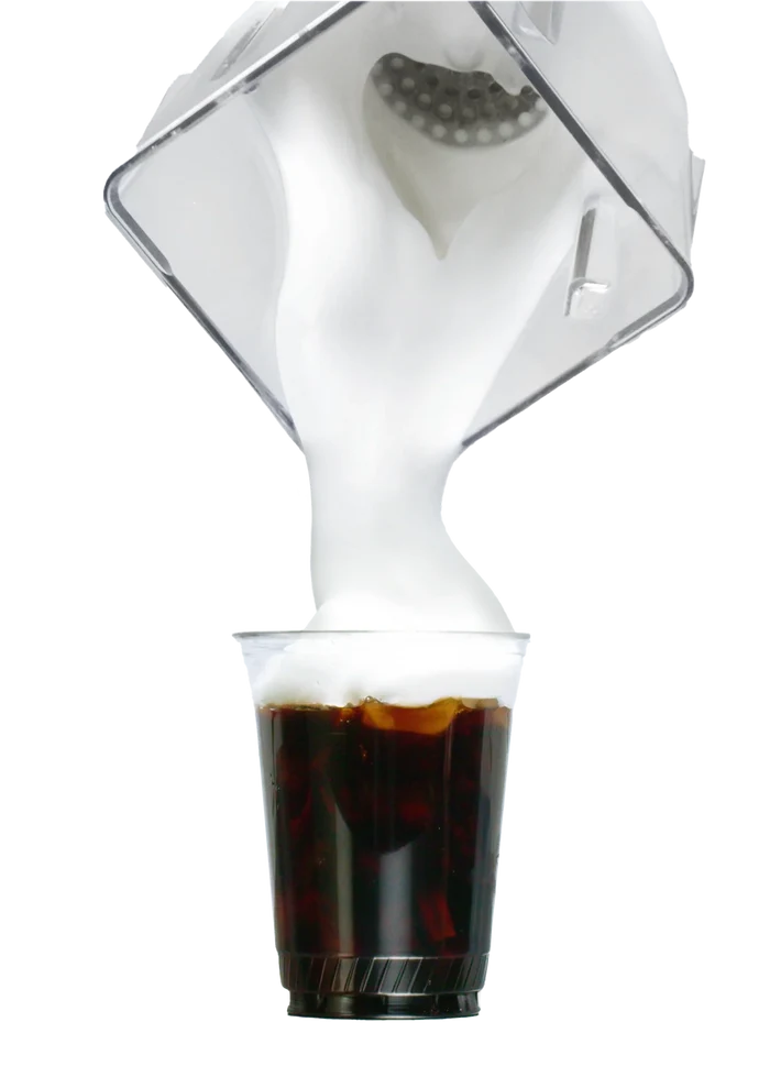 White coffee maker pouring liquid into a glass of coffee on a white background