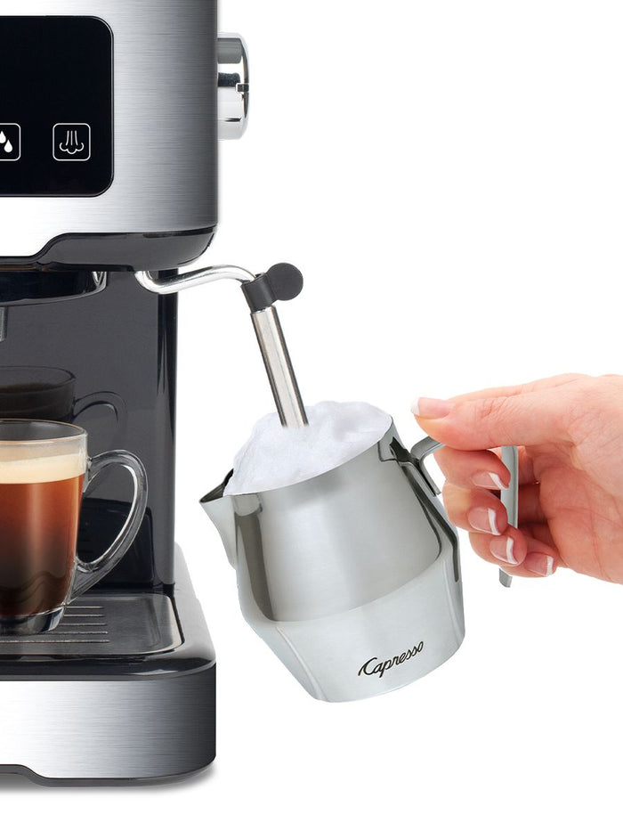 Someone frothing milk with a milk frother attached to Capresso coffee machine displayed on a white background