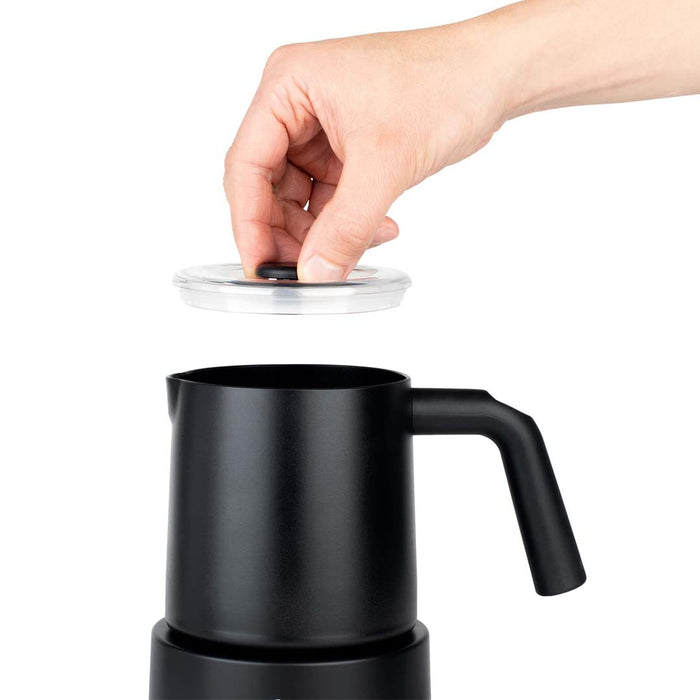 Someone placing a lid on black Capresso automatic milk frother displayed on a white background