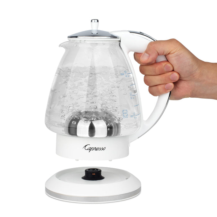 White and polished chrome Capresso 48 oz electric kettle with handle, held by a hand on a white background.