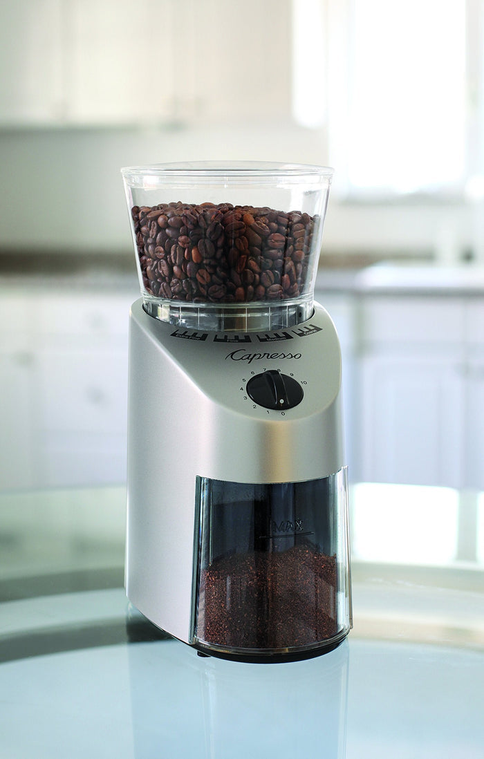 Capresso coffee grinder with coffee beans on a blurred kitchen background