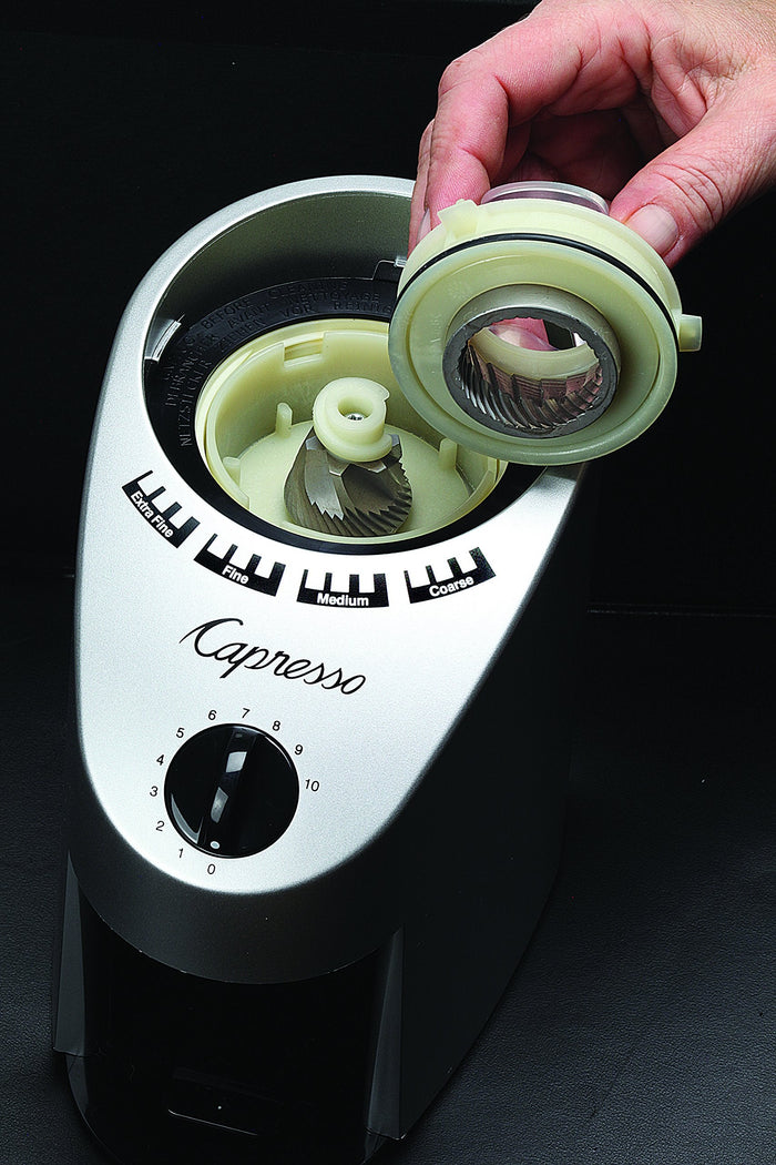 Capresso coffee grinder with a hand removing the blade on a black background