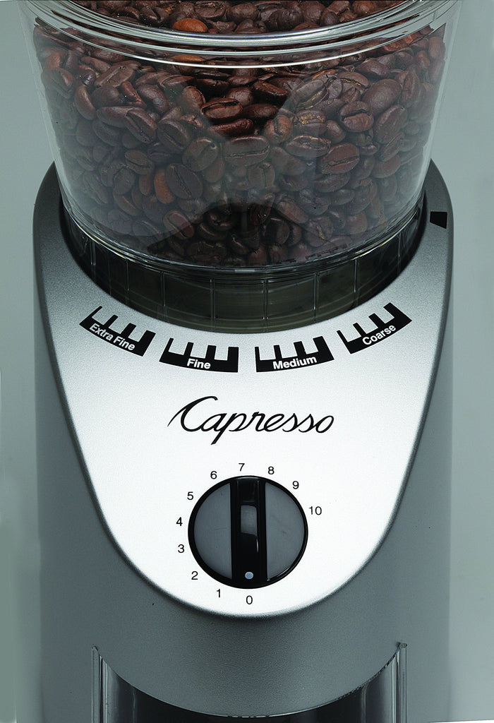 Close up of the dial on a Capresso coffee grinder with coffee beans inside on a gray background