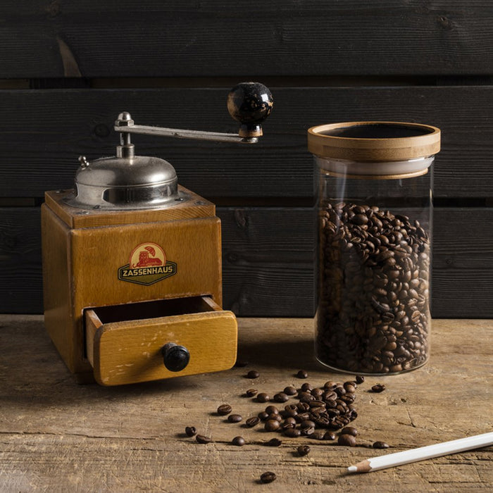Vintage coffee grinder with a jar of coffee beans on a wooden surface
