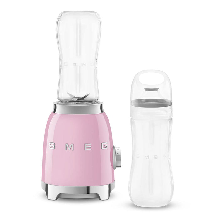 Pink Smeg retro line personal blender next to clear tumbler on a white background