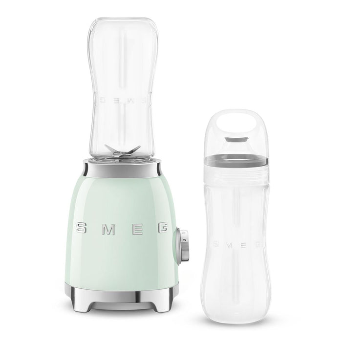 Pastel green Smeg retro line personal blender next to a clear tumbler on a white background