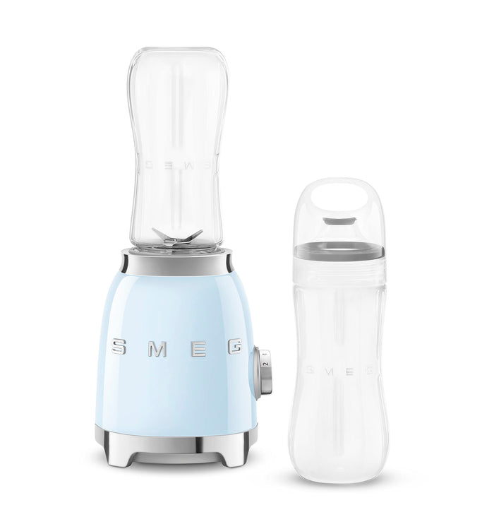 Pastel blue Smeg retro line personal blender next to clear tumbler on a white background