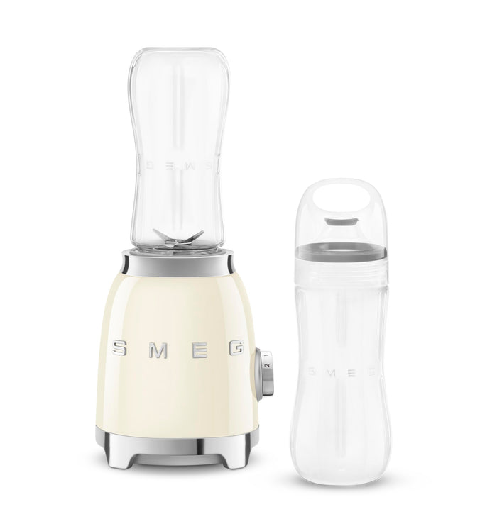 Cream Smeg retro line personal blender next to clear tumbler on a white background