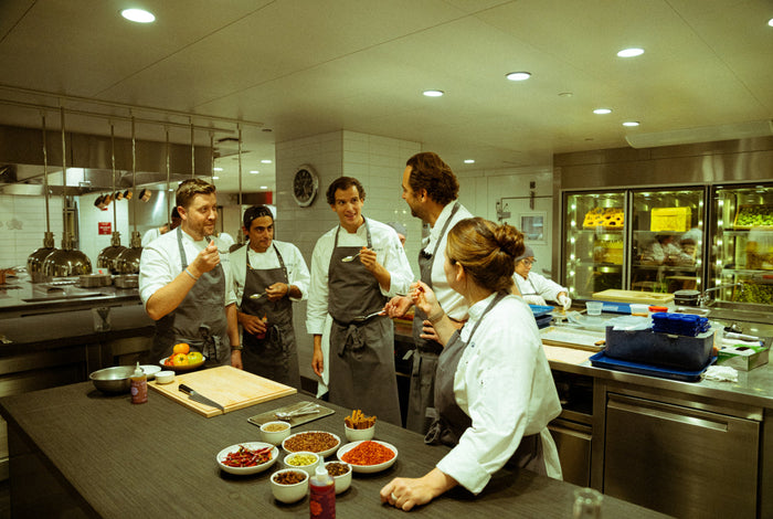 Group of chefs in a professional kitchen preparing food.