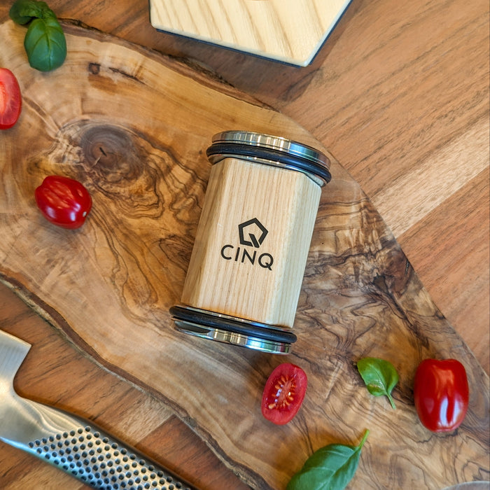 Cinq rolling knife sharpener on a wooden surface next to small tomatoes and a knife
