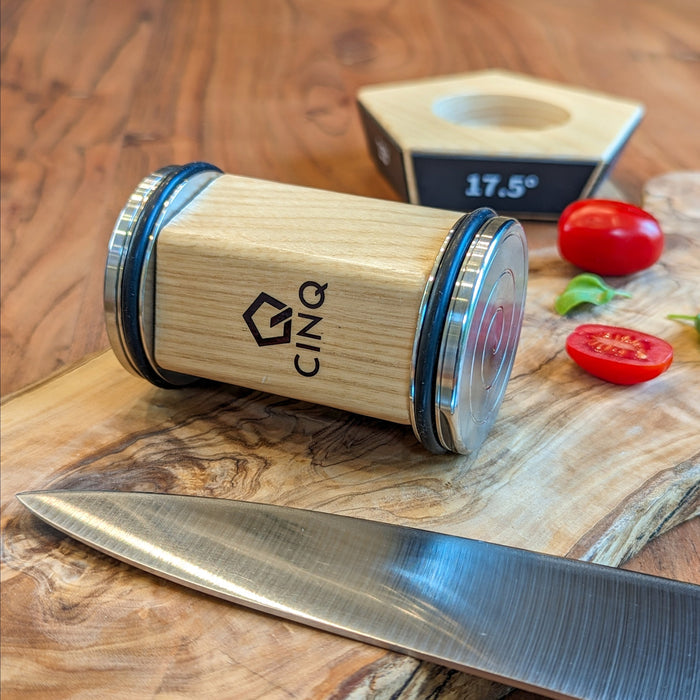 Cinq rolling Knife Sharper next to a knife and chopped tomatoes on a wooden surface