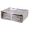 A folded slate gray twin XL Delilah home 100 organic cotton bed sheet set tied with a ribbon, on a white background.