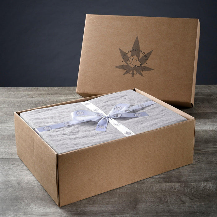 A folded Light Gray twin XL Delilah Home 100 organic Hemp Bed Sheet set tied with a ribbon, displayed in packaging on a wooden surface.