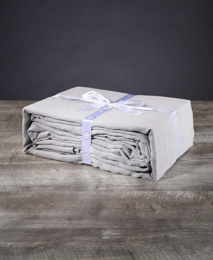 Folded gray blanket with a white bow on a wooden surface against a dark background