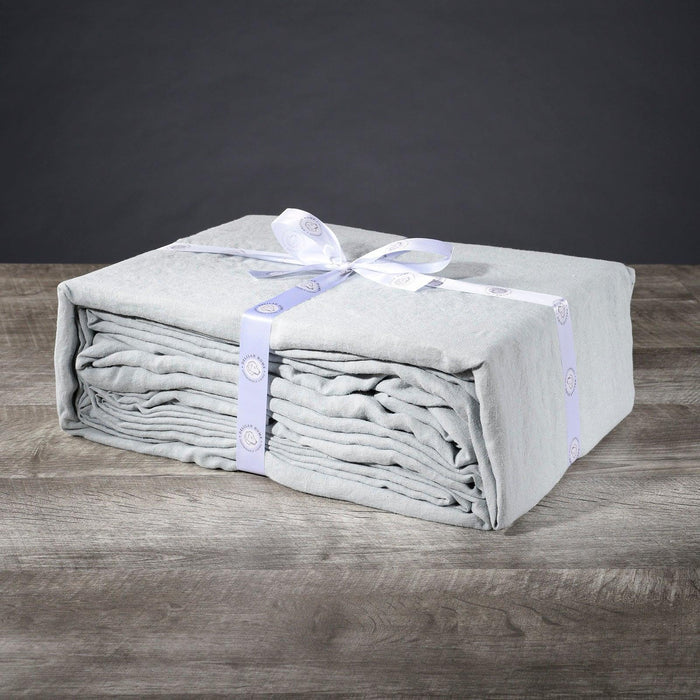 A folded mineral green twin XL Delilah Home 100 organic Hemp Bed Sheet set tied with a ribbon, displayed on a wooden surface.