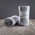 Two blue Delilah Home beach towels on a wooden surface and grey background