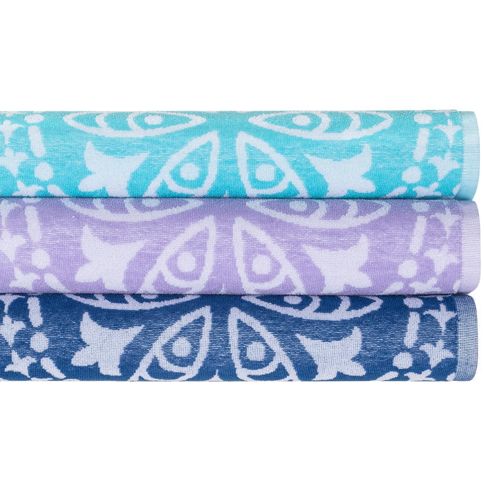 A stack of three Delilah home beach towels in blue and purple colors with a white paisley pattern.