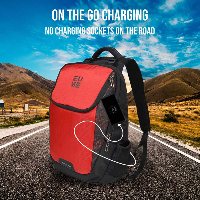 Red and black Eume backpack sitting on a road surround by hills and the sky with phone charging with built-in USB port and text "On The Go Charging No Charging Sockets On The Road"