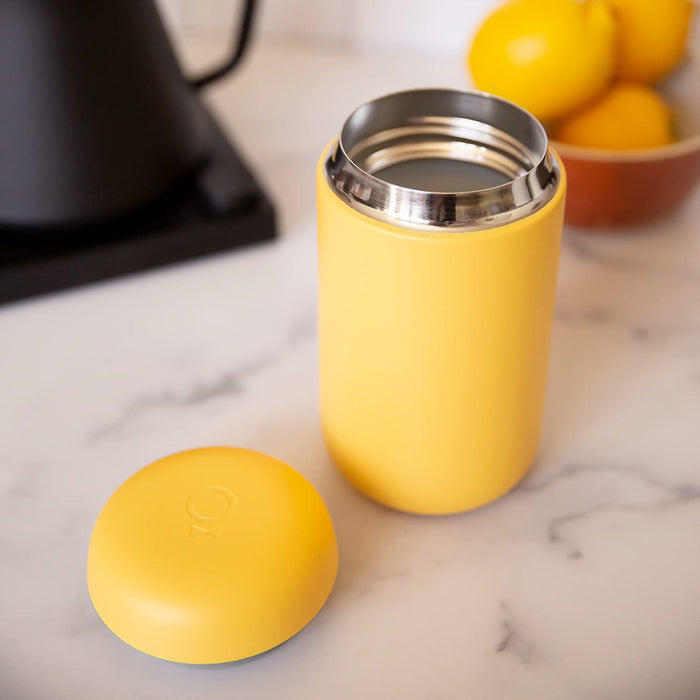 Yellow thermos with a matching yellow cap on a marble surface.