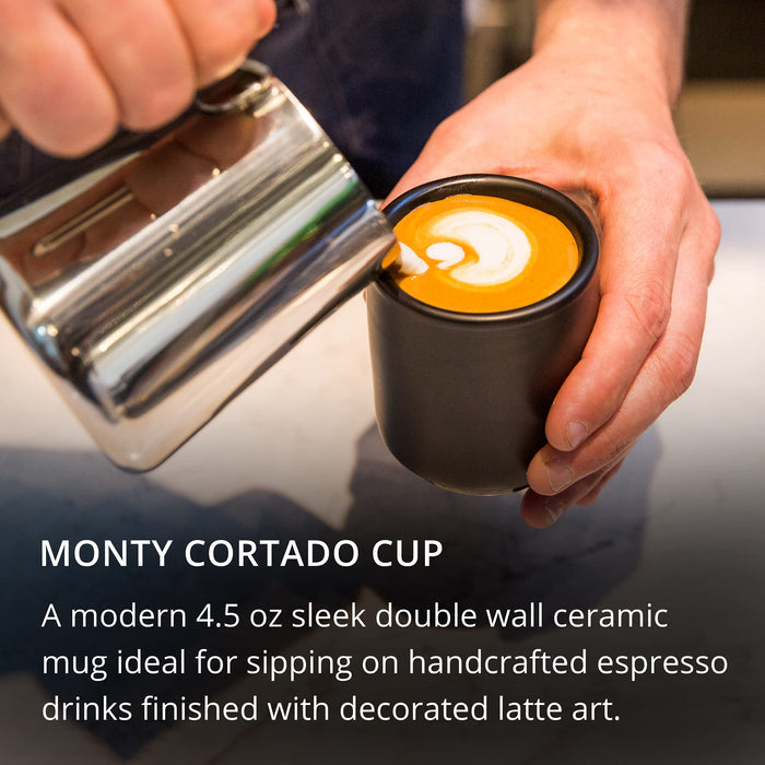 Person pouring milk into a Monty Cortado Cup with latte art.