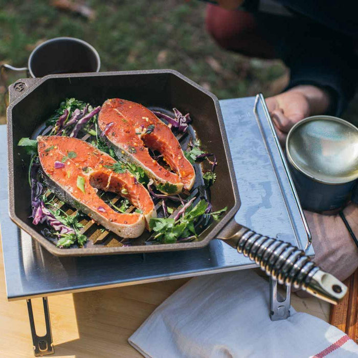 FINEX 10″ Cast Iron Grill Pan, Grillet displayed outside with food being grilled
