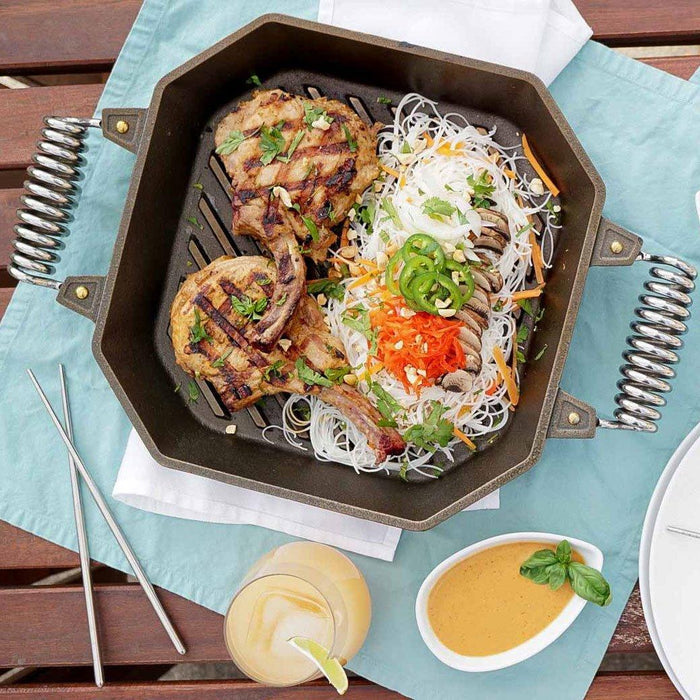 FINEX 12″ Cast Iron Grill Pan with cooked food on the pan displayed on a table outside