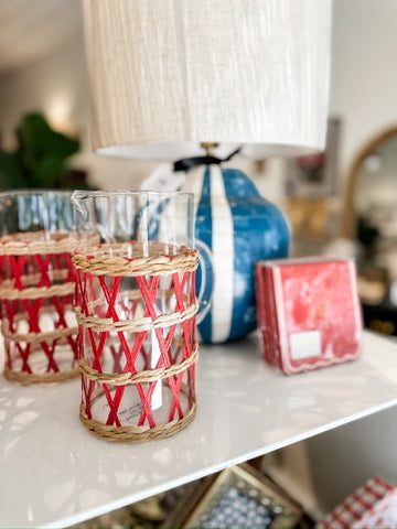 Glass pitcher with woven sleeve.