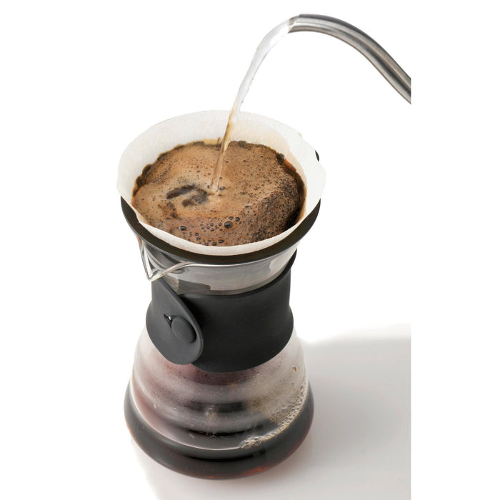 Top view of someone pouring water into Hario drip decanter displayed on a white background