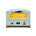 Front view of mint green toaster oven with a clear door showing yellow light on a white background