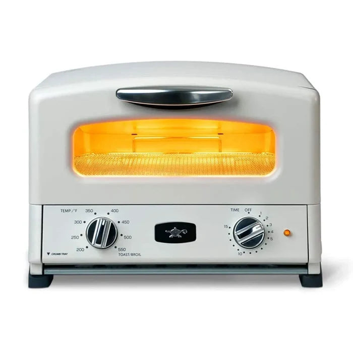 A toaster oven with a white exterior, black feet and handle, and an illuminated orange-yellow heating element visible through the front window. The front panel has two rotary dials, temperature and time settings, and a small orange power indicator light.