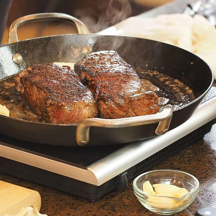 ICON Griddle - 12″ with two beef being cooked on a portable stovetop