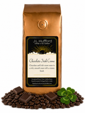 1 lb Chocolate Irish Creme coffee beans bag with coffee beans, blocks of chocolate, and four-leaf clover in front displayed on a white background