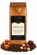1 lb J.L. Hufford Highlander Grogg coffee bag with coffee beans, blocks of caramel, hazelnuts, and spice on a white background
