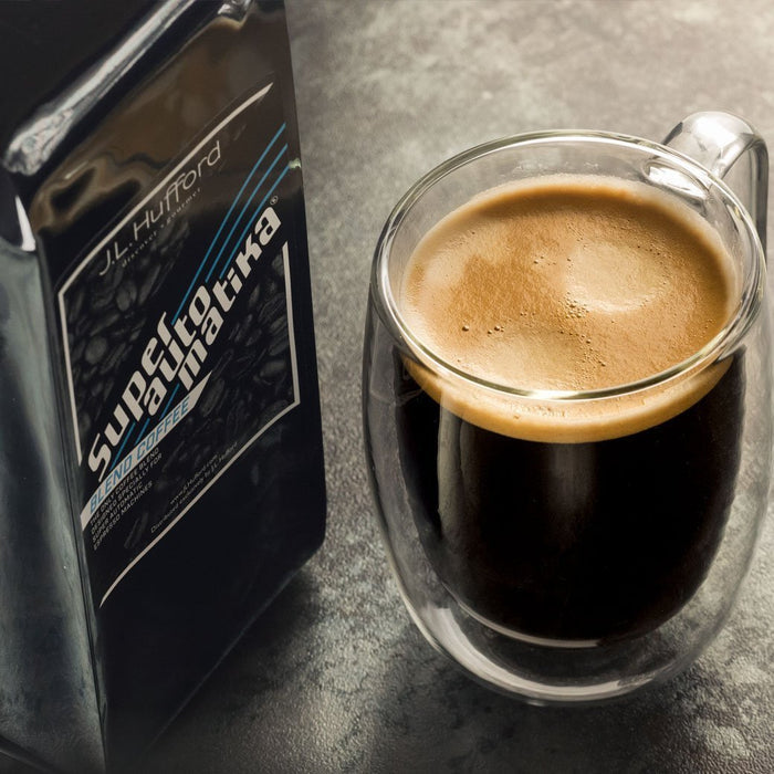 1 lb J.L. Hufford Superautomatika Blend Coffee bag next to a coffee-filled glass on a countertop