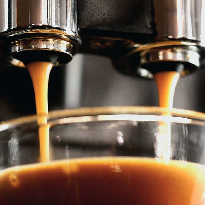 An espresso machine pouring out coffee into a clear glass