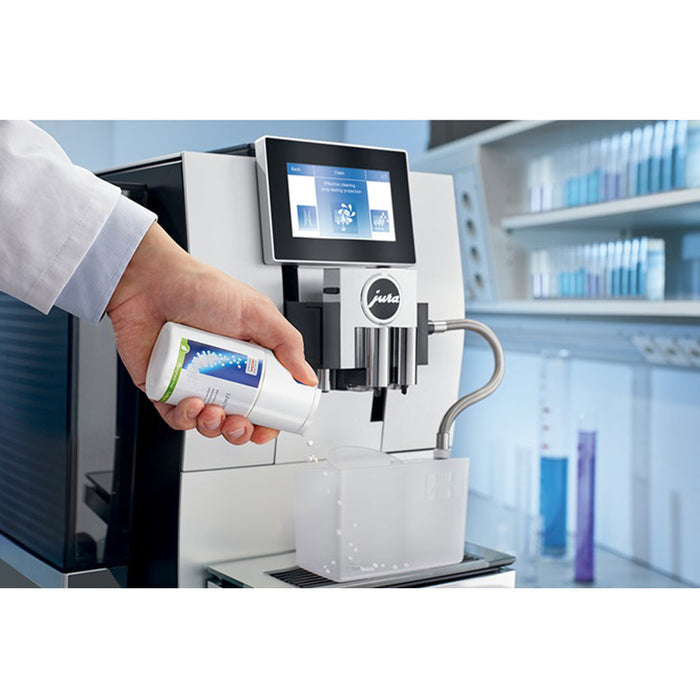 Someone dispensing Jura milk system cleaner mini tabs into a Jura container attached to a Jura coffee machine