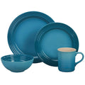 Set of Caribbean Le Creuset bowl, mug, and plates displayed on a white background