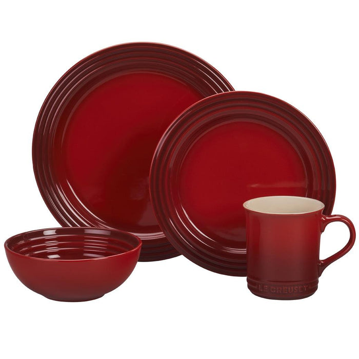 Set of Cerise Le Creuset bowl, mug, and plates displayed on a white background