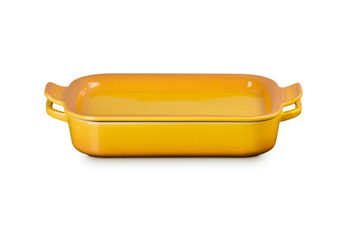 A rectangular yellow ceramic baking dish with side handles and lid, shown on a clean white background.