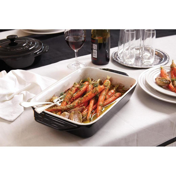 Black Le Creuset 3.5 qt. Covered Rectangular Casserole with baked carrots displayed on a dinner table