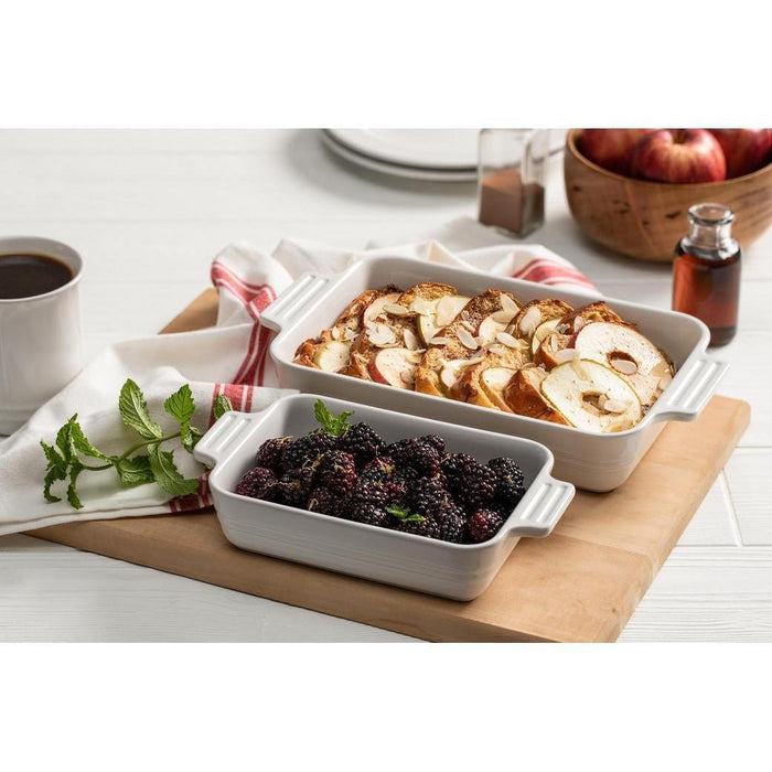 2 white Le Creuset 3.5 qt. Covered Rectangular Casserole with toasted bread and blackberries displayed on a board next to applies and coffee