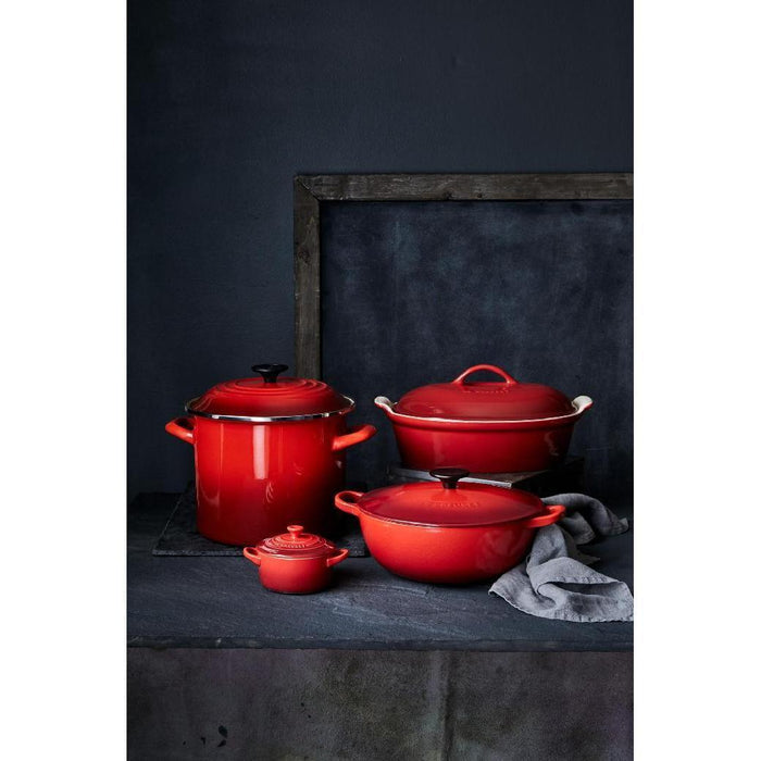 Set of red Le Creuset cookware displayed on a dark background