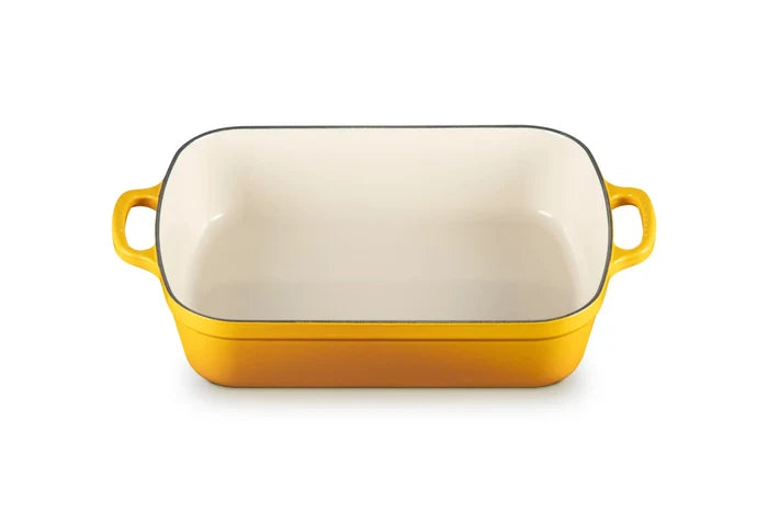 A rectangular yellow enameled baking dish with a cream-colored interior and two yellow side handles, shown on a plain white background.