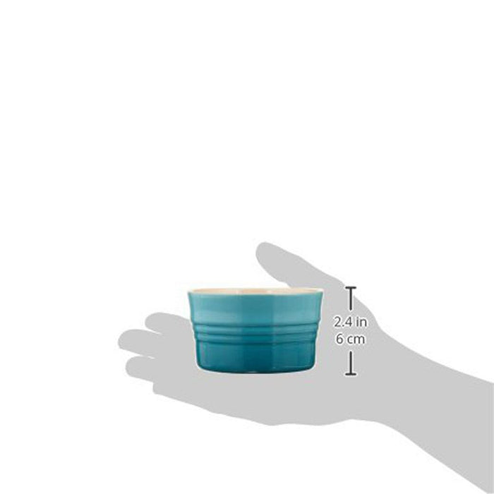 Caribbean Le Creuset 7 Oz Stoneware Stackable Ramekin with dimensions and a shadow of a person's hand displayed on a white background
