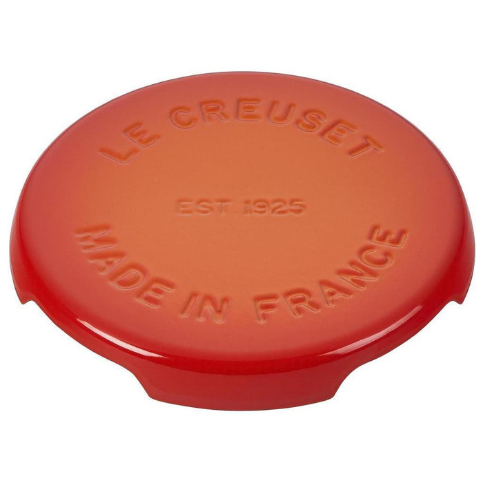 8.8 inch flame Le Creuset enameled cast iron signature trivet displayed on a white background