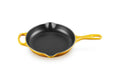 A yellow enameled cast iron skillet with a black non-stick interior, featuring a single loop handle and a small side handle, shown on a solid white background.