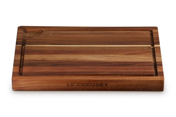 Wooden cutting board with 'Le Creuset' branding on a white background