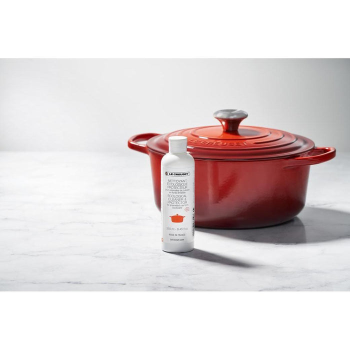 Le Creuset Cast Iron Cookware Cleaner and Protector in front of a Le Creuset cast iron pot displayed on a marble surface