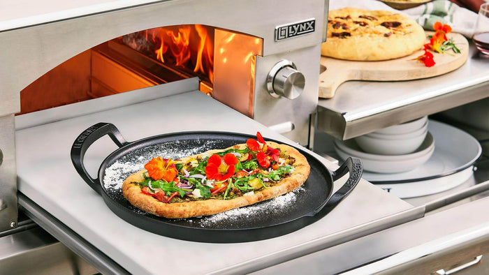 Lynx pizza oven with a pizza being cooked inside, surrounded by kitchen items.